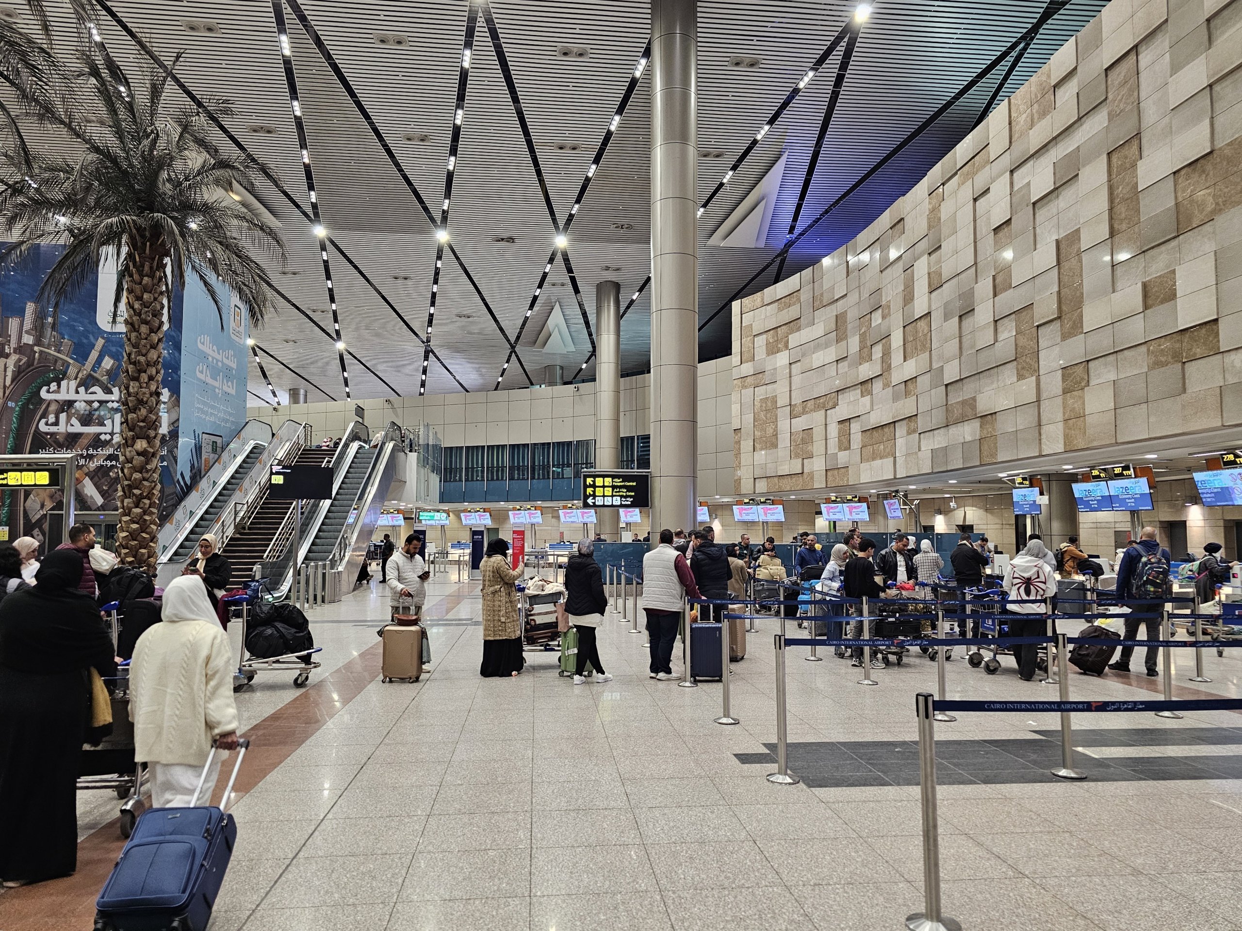 Travelers with luggage inside the arrivals hall at Cairo International Airport